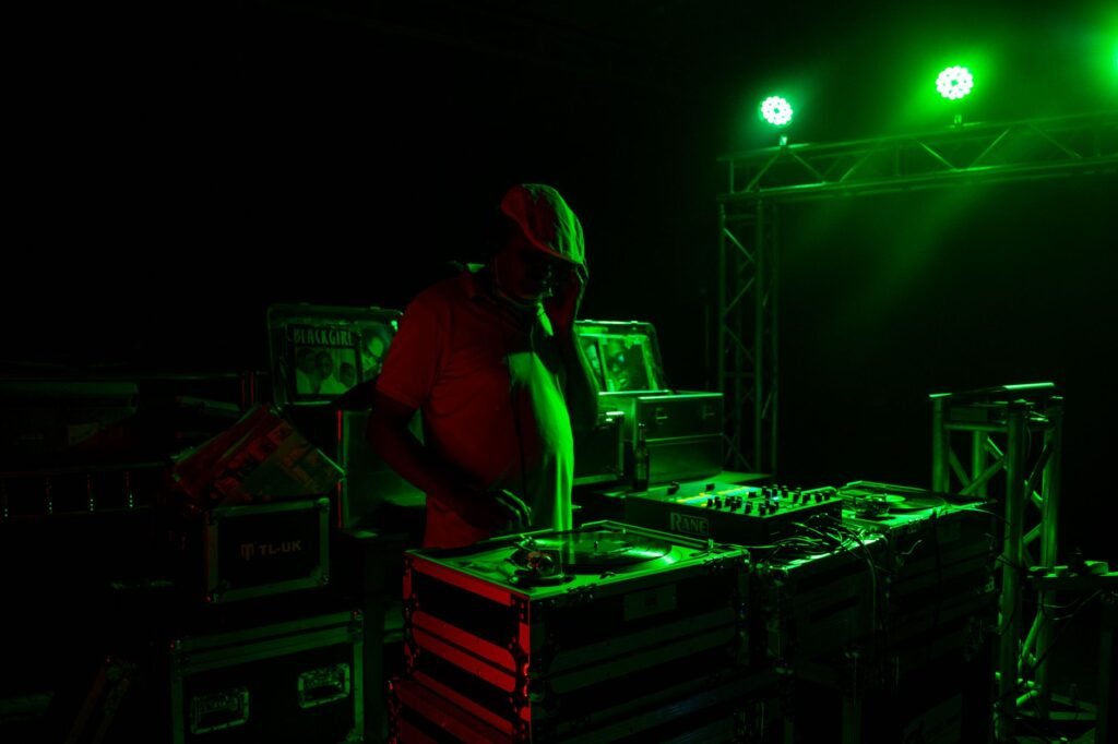 DJ mixes tracks under green spotlights in a lively club atmosphere.