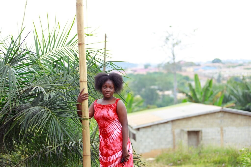 Portrait of a woman in a red tie-dye dress outdoors, holding bamboo.