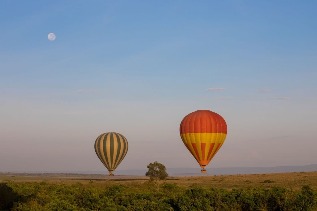 Beautiful hot air balloons floating over the Kenyan savanna under a clear sky and full moon.