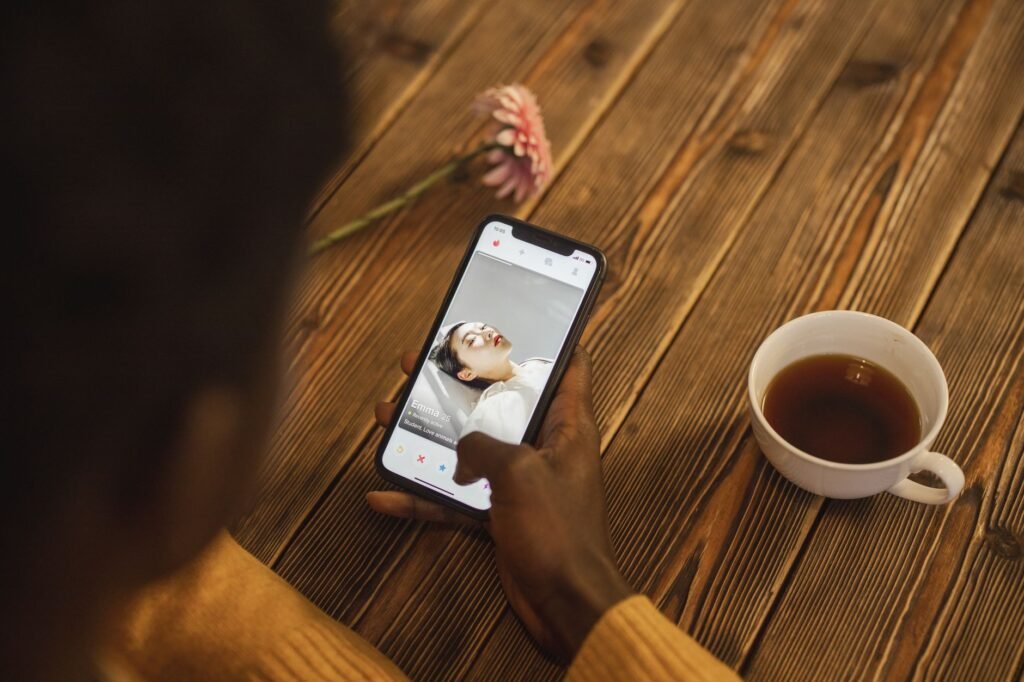 Smartphone on a wooden table next to a cup of tea, representing online browsing