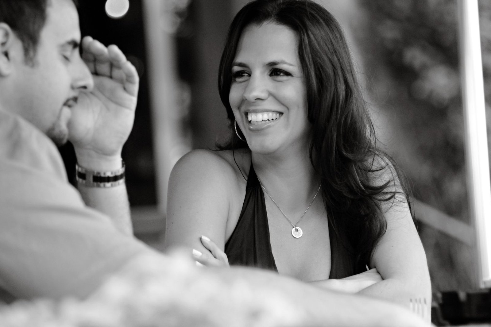 A candid black and white photo of two adults enjoying a conversation at a cafe in Miami Beach.