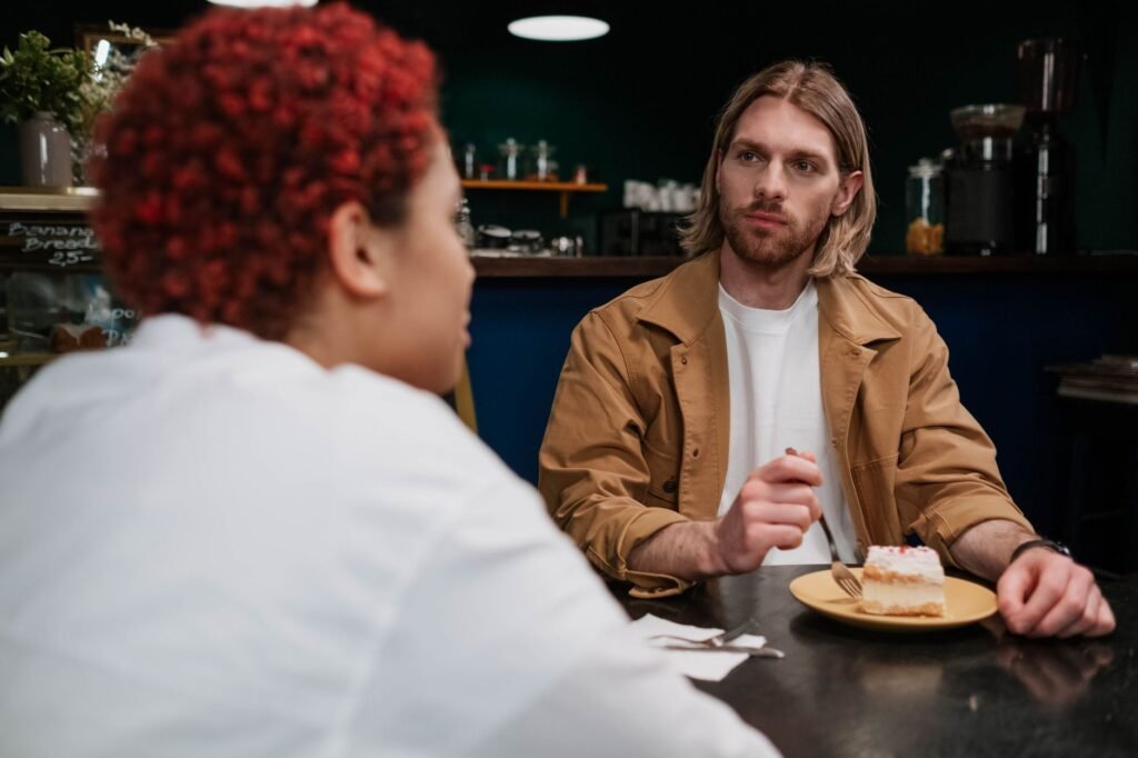 A couple having a thoughtful conversation over dessert in a cozy cafe setting.