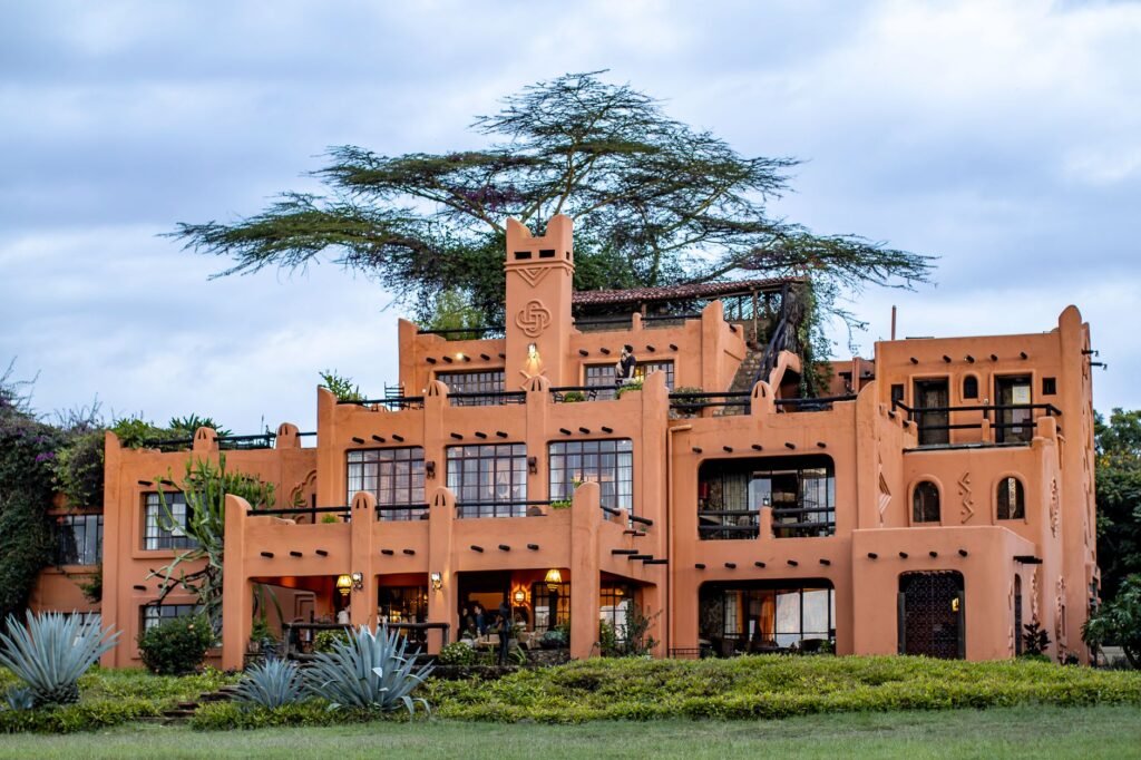 A traveller in modest light clothing sitting outside a small guesthouse at dusk in an arid Kenyan town