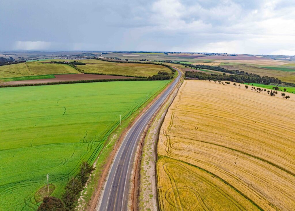 Vibrant aerial shot of farmlands and road in Mau Narok, Kenya on a cloudy day.