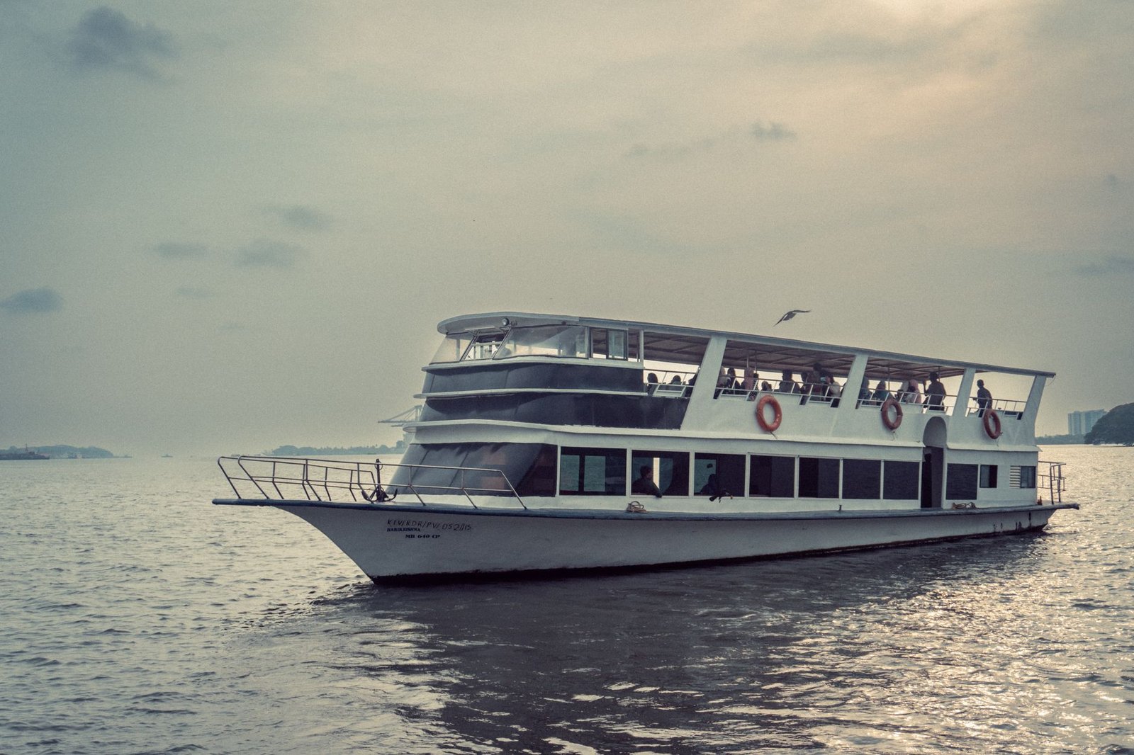A serene white ferry boat sailing on calm waters in India during daytime, capturing tranquil ambiance.