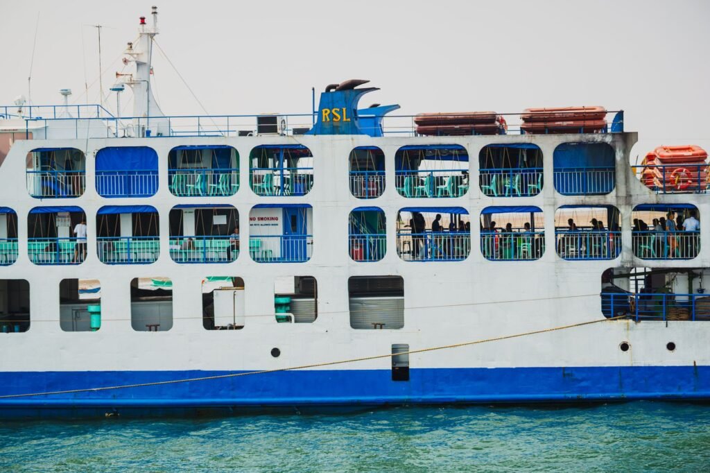 Side view of a passenger ferry with blue accents, showcasing people onboard and lifeboats.