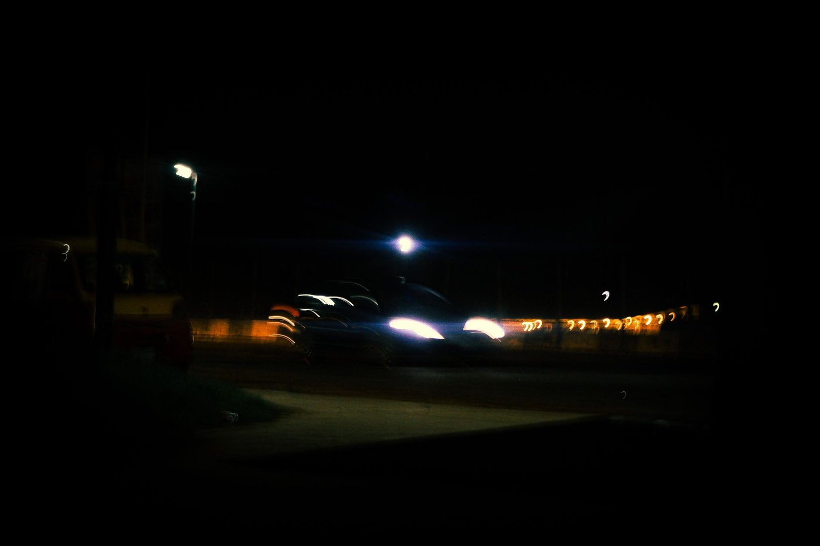 A moody urban night scene with blurred car headlights and street lamps, creating a dynamic atmosphere.