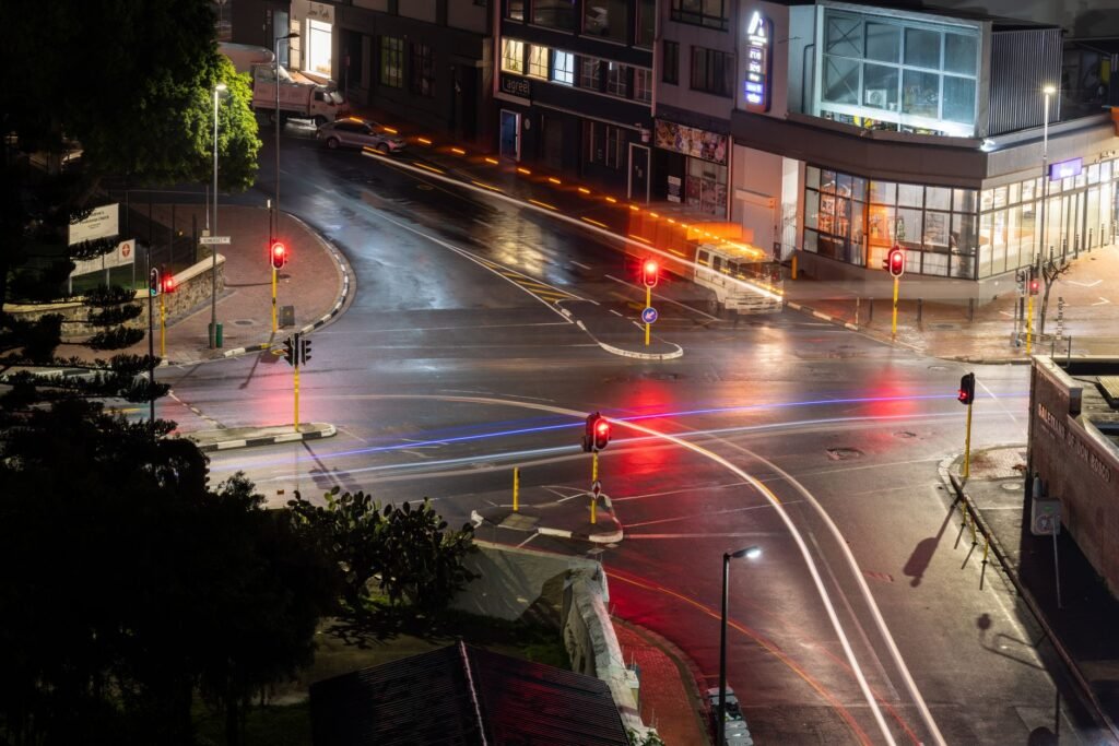 A nighttime long exposure capturing light trails and illuminated streets at an urban intersection.