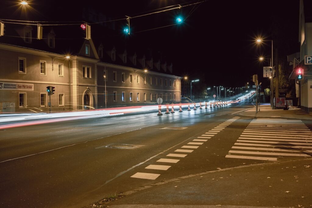 Moody street with trails of car lights and city architecture at night.