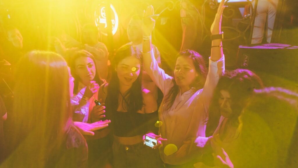 Group of friends enjoying a lively night out at a club with vibrant yellow lighting and music.