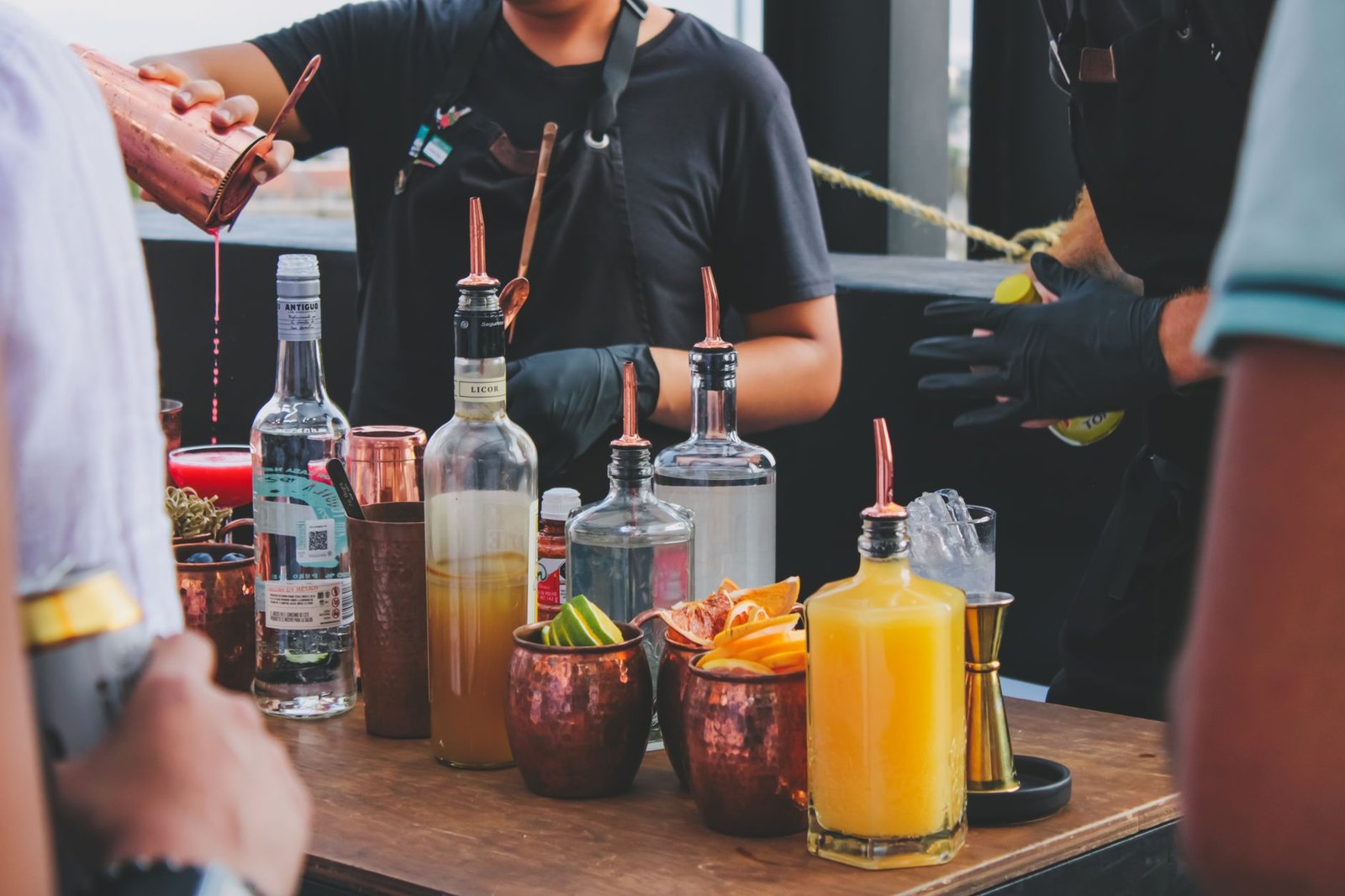 Bartender skillfully prepares vibrant cocktails at a rooftop bar with an array of spirits.