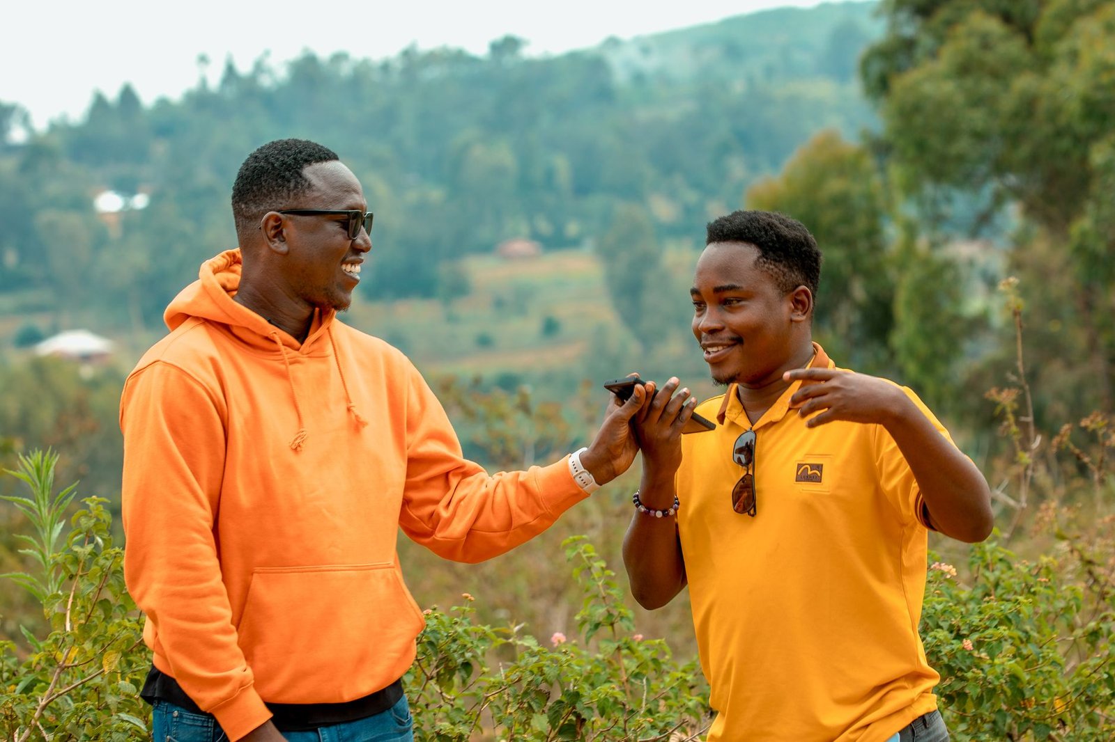 Two friends enjoying a lively conversation in rural Homa Bay, Kenya, surrounded by lush greenery.
