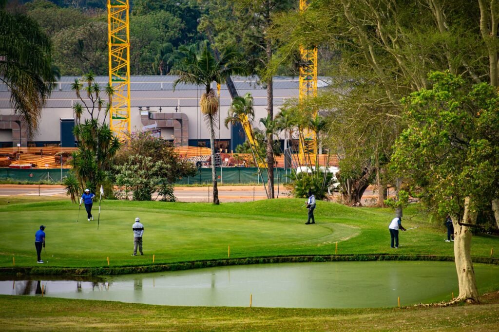 People golfing surrounded by scenic nature and construction in Piggs Peak, Eswatini.