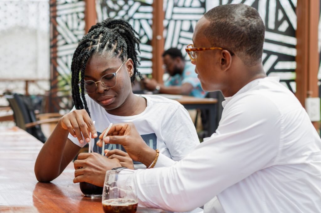 Young couple enjoying a shared drink at an outdoor cafe in Accra, Ghana.