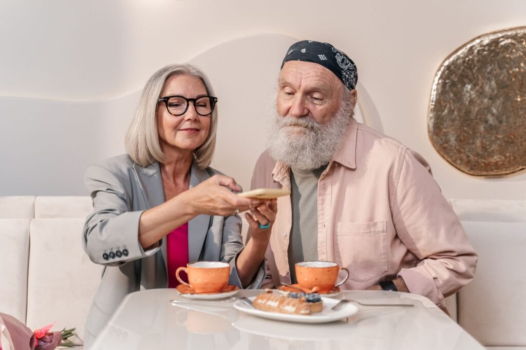 A happy senior couple shares coffee and pastries at a cozy café.