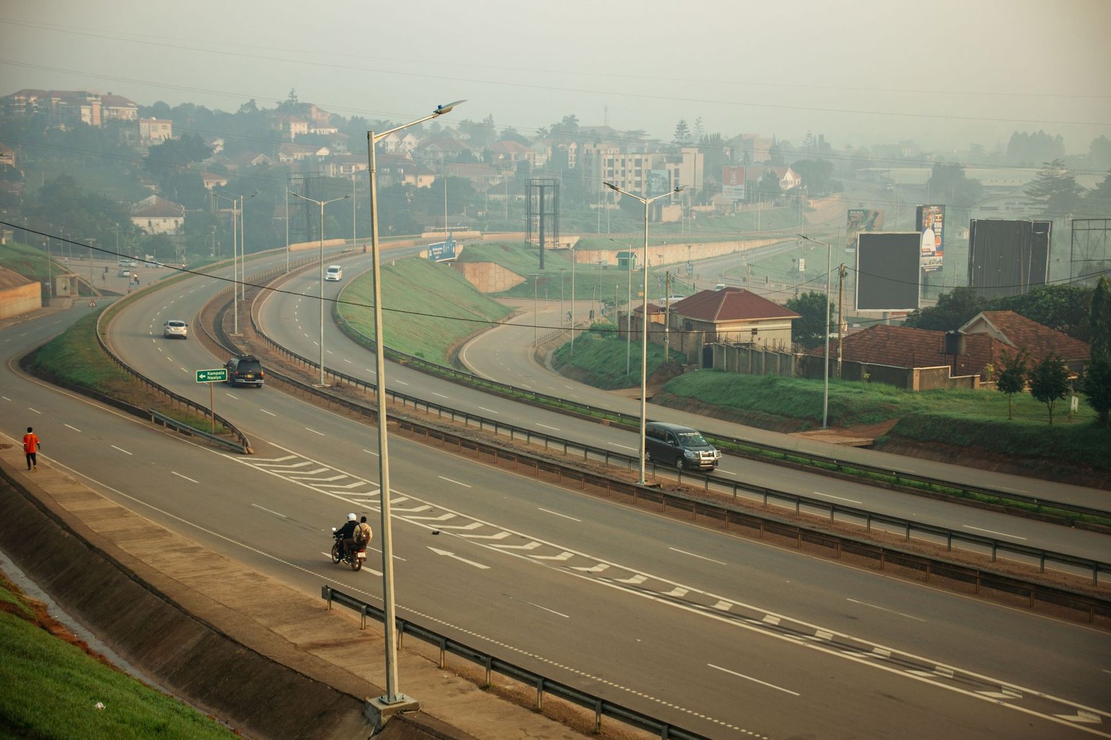 Early morning view of a curved highway in an urban setting with vehicles and light traffic.