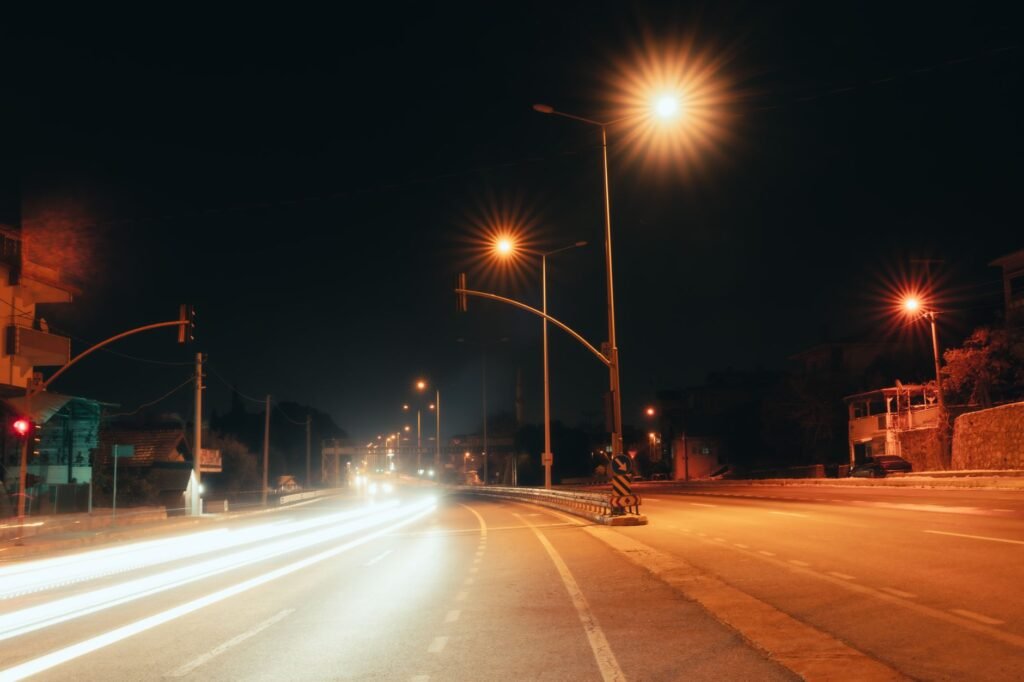 A serene night scene with bright street lights and light trails on an empty city road.
