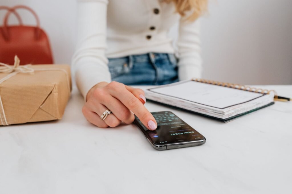 Hands holding a smartphone beside a notebook, planning a booking message