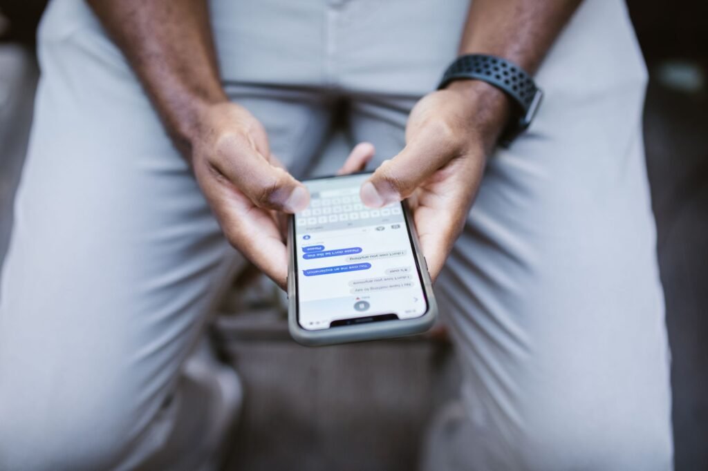 Hands holding a smartphone while writing a message at a table