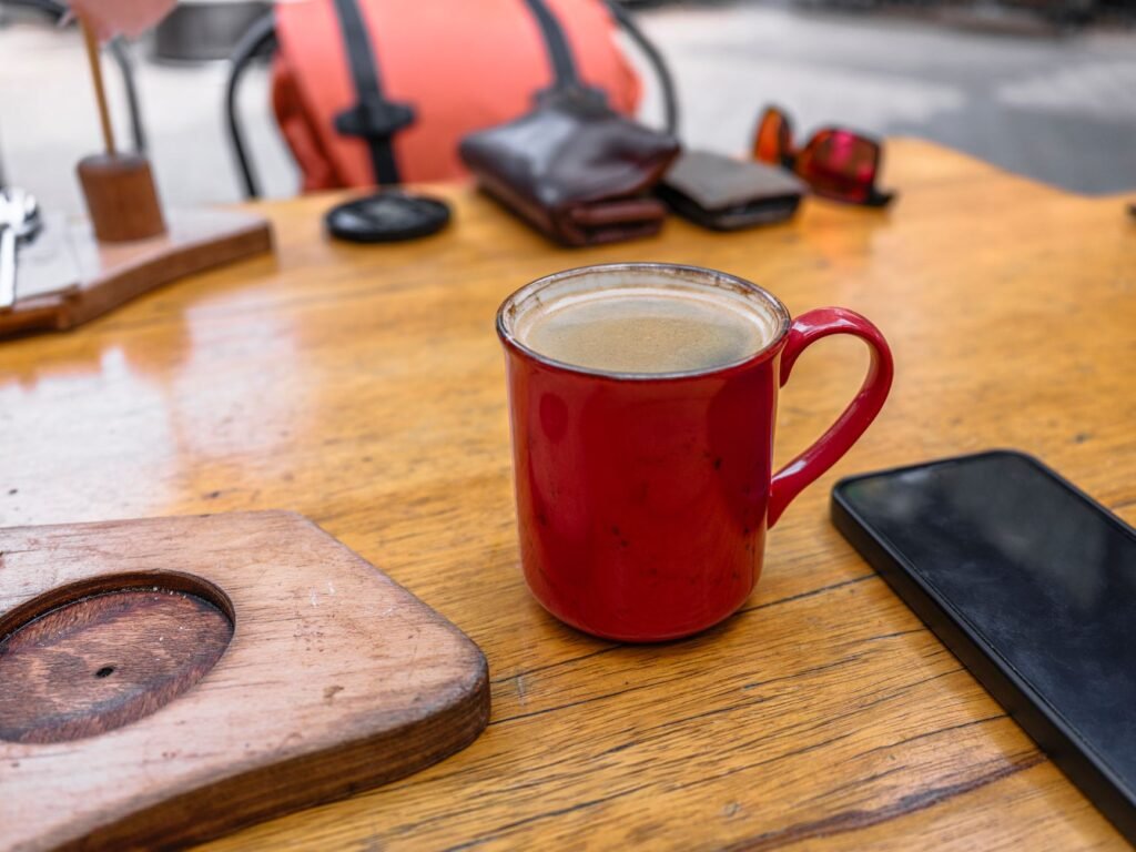 Smartphone on a cafe table next to a cup of tea in soft daylight