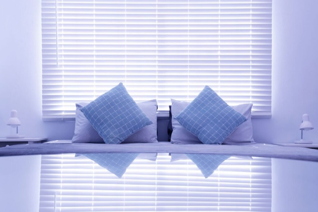 Neat guesthouse room in northern Kenya with a made bed, side table and soft afternoon light through partly drawn curtains