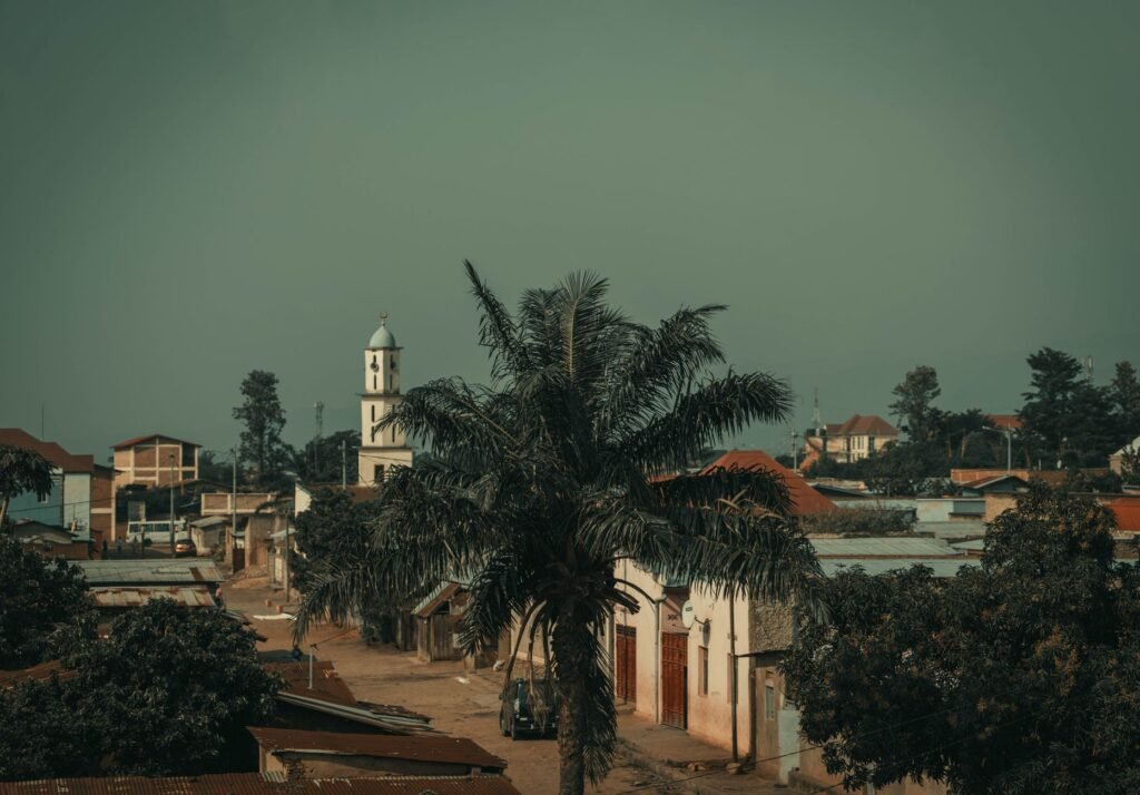 Scenic view of Bujumbura cityscape featuring a prominent church tower and palm tree.