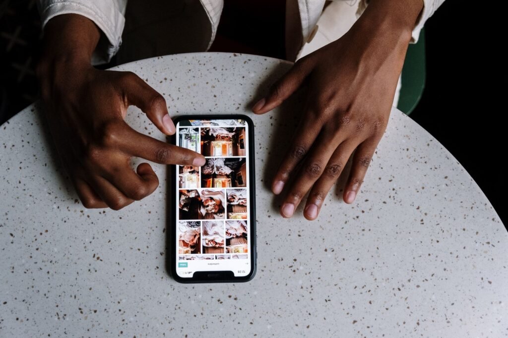 Person browsing a directory on a smartphone at a wooden cafe table in daylight