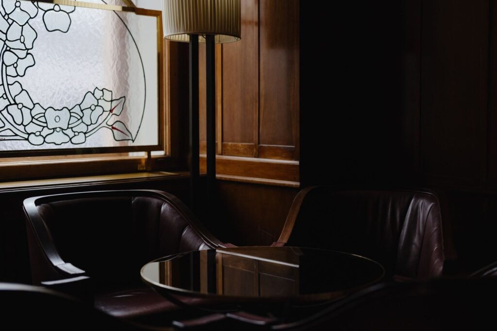 Sophisticated lounge interior with dark wood paneling and artistic stained glass window design.