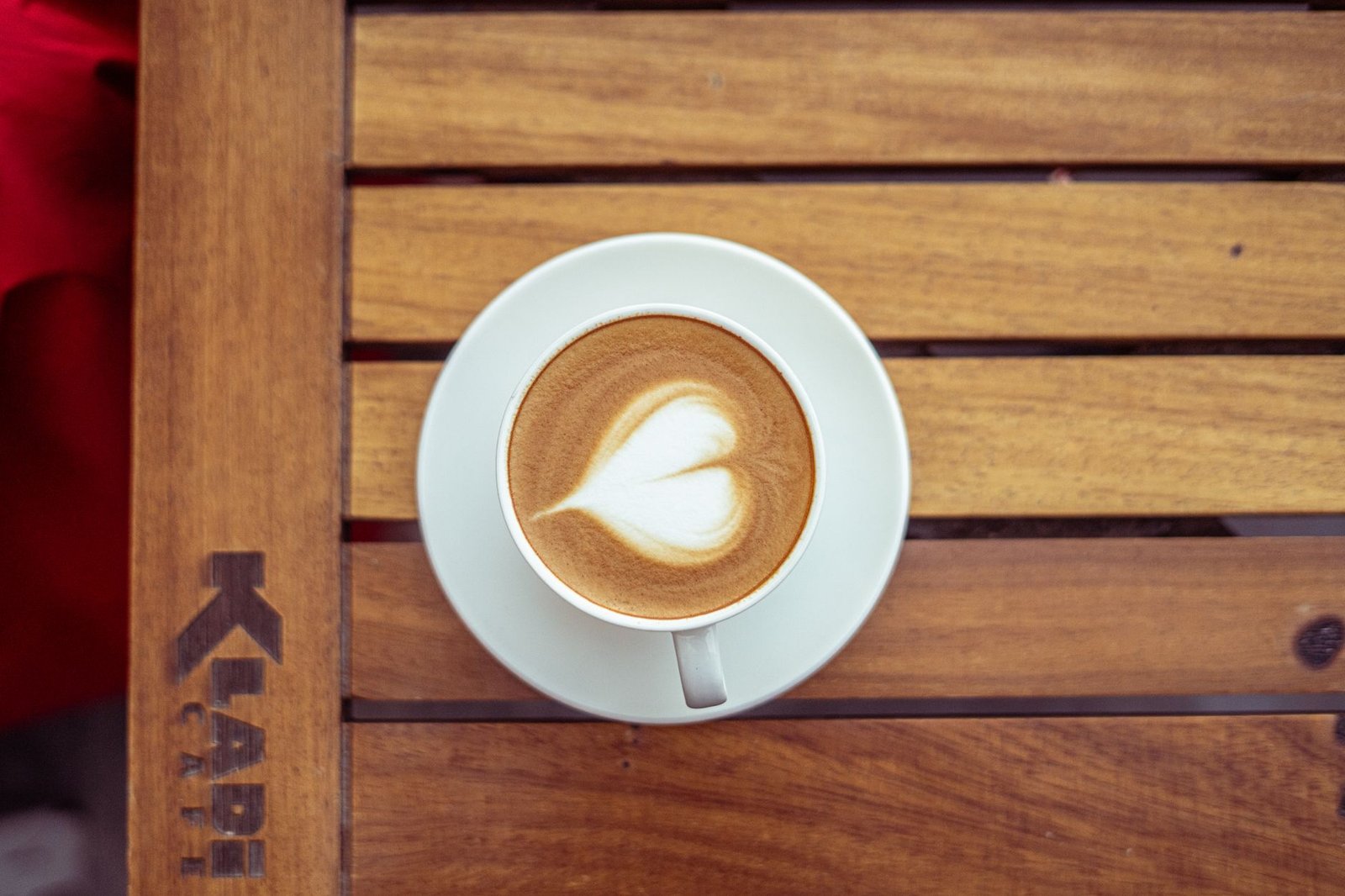 A creamy latte with heart-shaped art on a wooden table at a cafe in Baghdad.