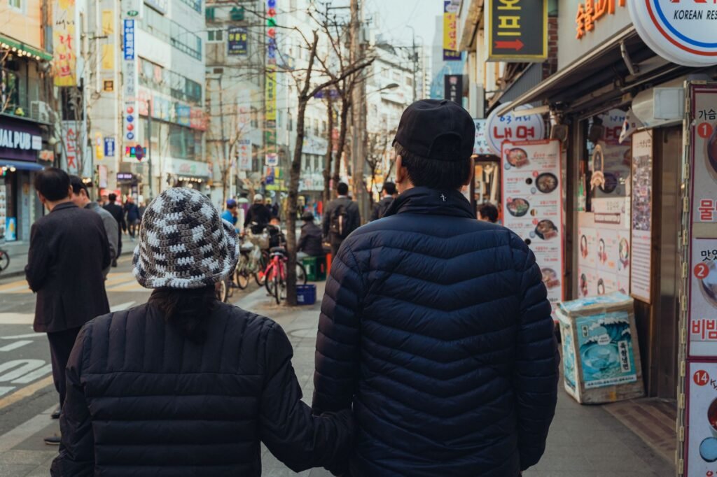 A couple strolls through a vibrant street in Seoul, capturing daily city life.