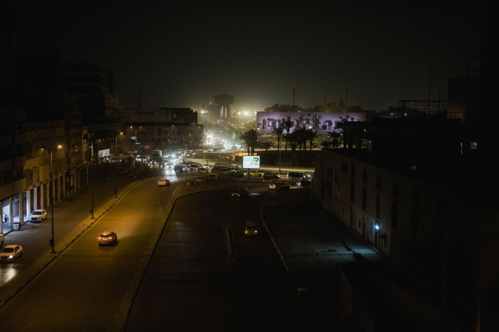 Aerial view of a city street at night with glowing streetlights and vibrant building lights creating a dramatic atmosphere.