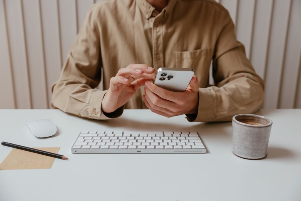 Person reading a directory listing on a smartphone at a desk in natural light