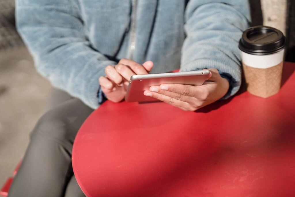 Hands holding a smartphone at a table while reading a profile