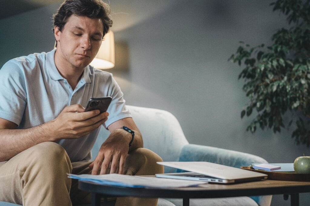 A person reading a smartphone carefully on a sofa in daylight