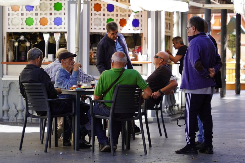 Two people meeting politely at an outdoor café table in daylight