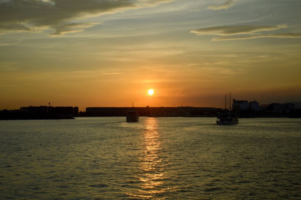 Serene sunset view over waterfront with boats and glistening waters reflecting the warm hues.