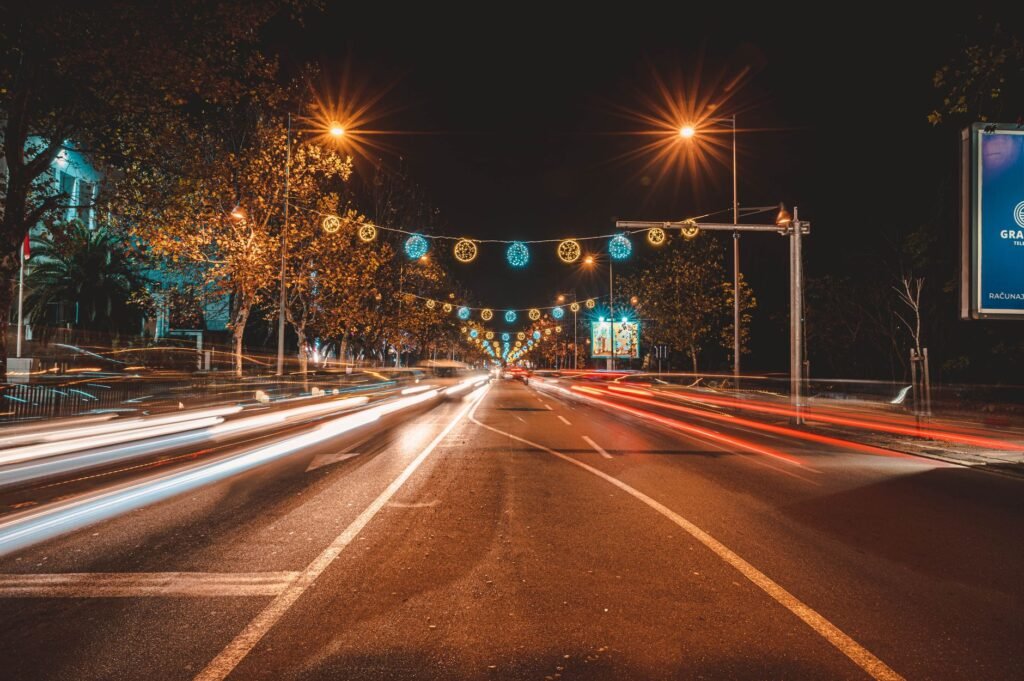 Vibrant city street in Podgorica, Montenegro with festive lights and long exposure traffic trails at night.
