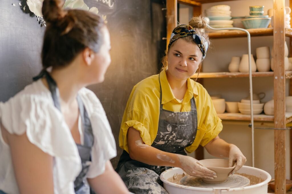 Two women engaged in pottery making indoors, focusing on creativity and craftsmanship.