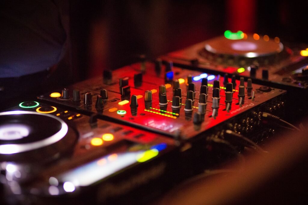 Close-up of colorful DJ mixer with glowing lights in a nightclub atmosphere.