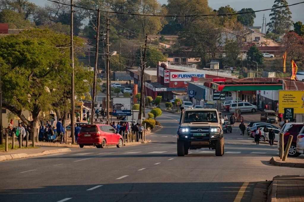 Busy street in Piggs Peak, Eswatini with pedestrians and vehicles on a sunny day.