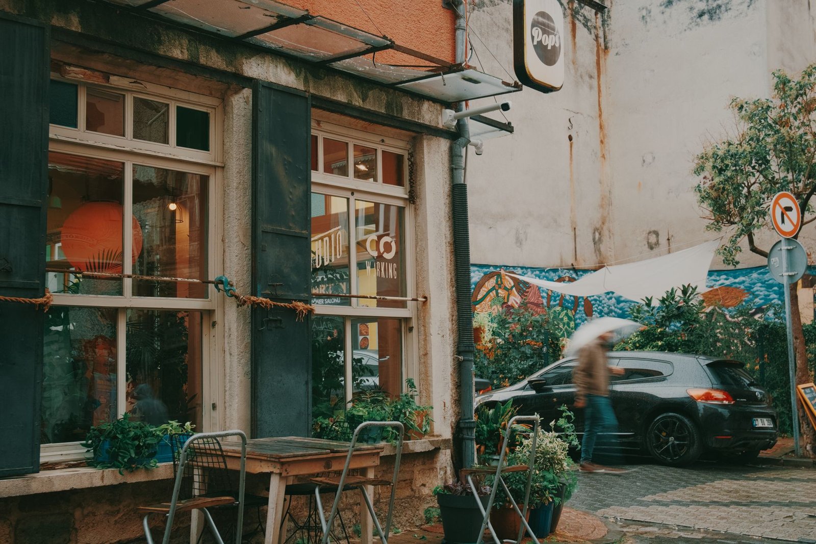 Cozy street café with outdoor seating and vibrant mural, ideal for urban lifestyle scenes.