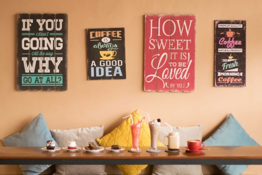 Cozy café interior with drinks and desserts on a wooden table, surrounded by artistic wall decor.