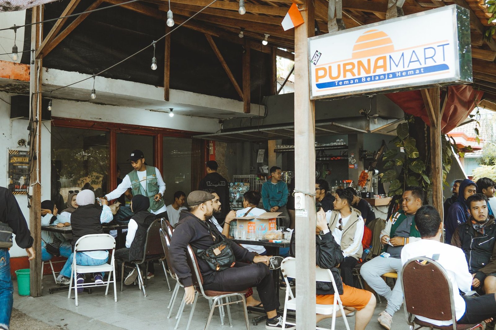 A bustling outdoor cafe in East Java with people enjoying a social gathering.