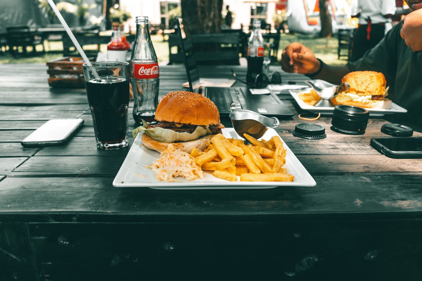Enjoying a delicious burger and fries with cola at a cozy outdoor café in Kenya.