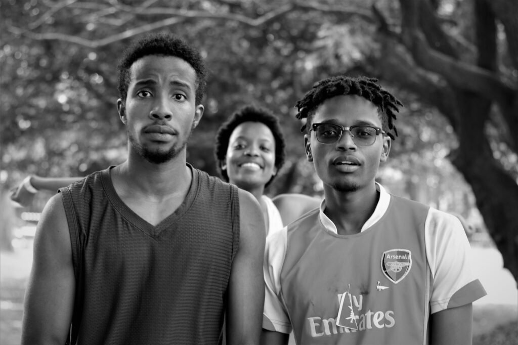 Three young adults in Nairobi park enjoying a sunny day outdoors.