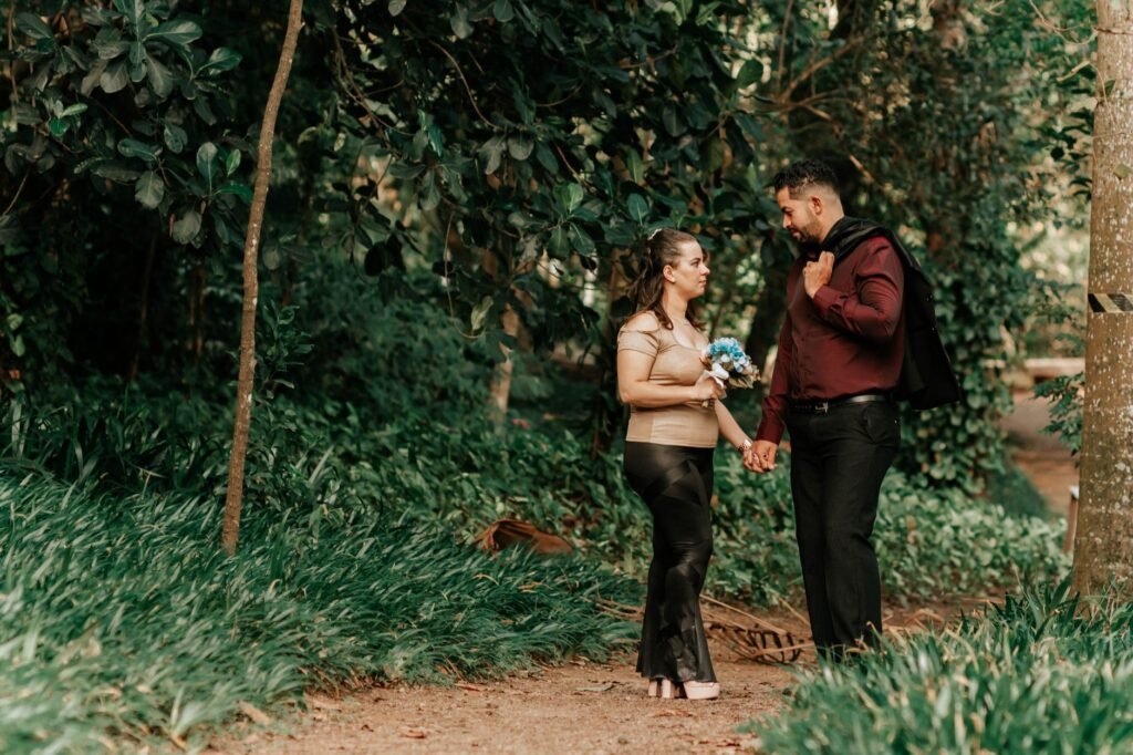 A couple holding hands and walking in a lush green park, symbolizing romance and togetherness.