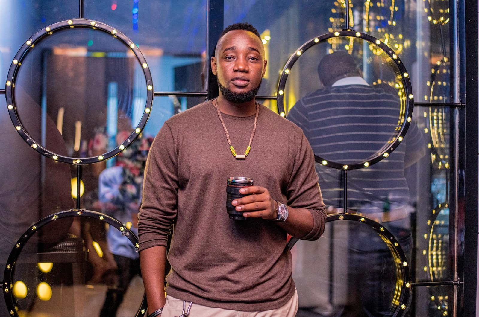 Casually dressed man enjoying nightlife with a drink in a modern urban setting.