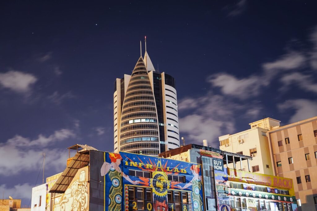 A vibrant night view of Haifa's iconic Sail Tower surrounded by colorful street art under a starry sky.