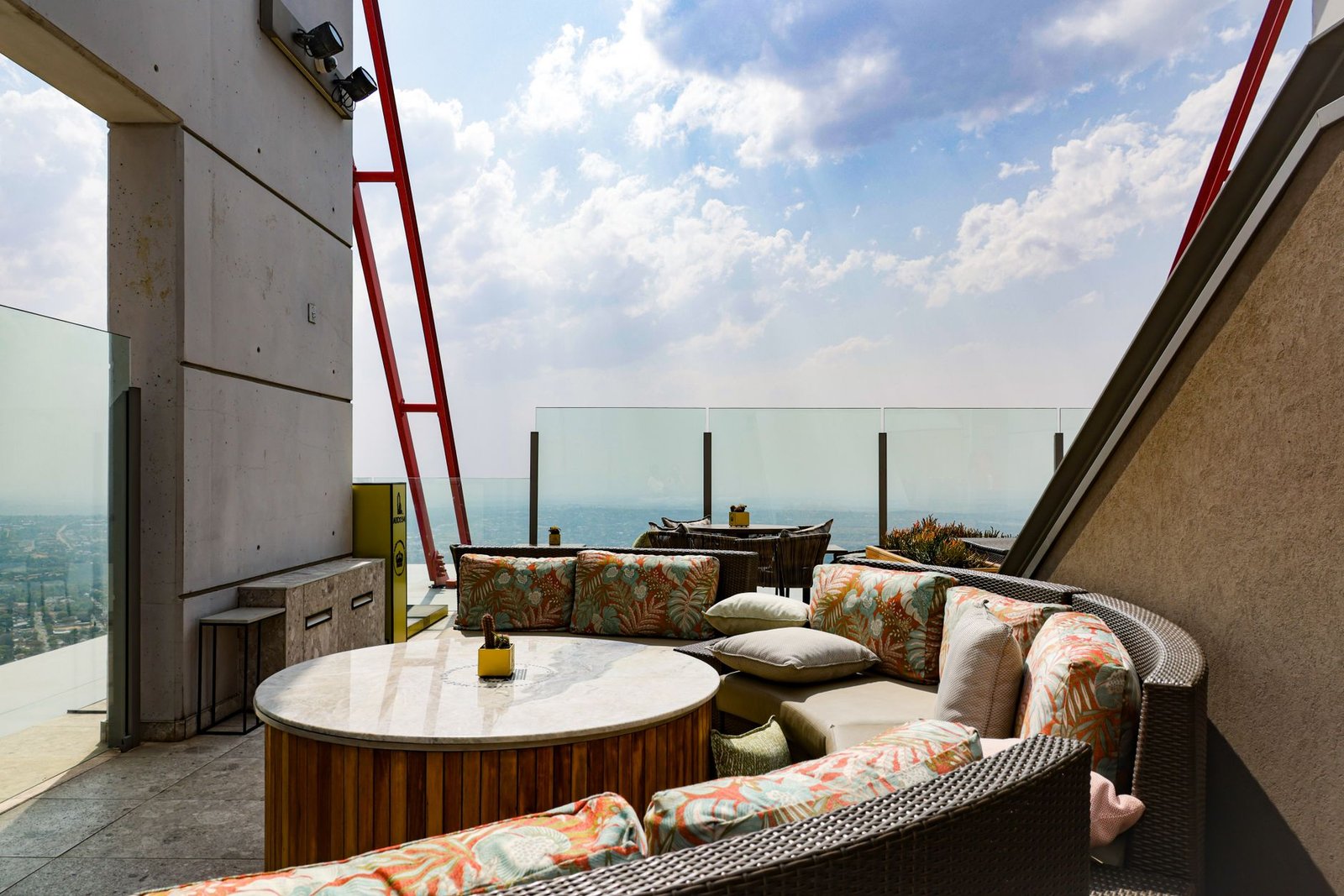 Stylish rooftop lounge offering panoramic city views under a sunny sky.