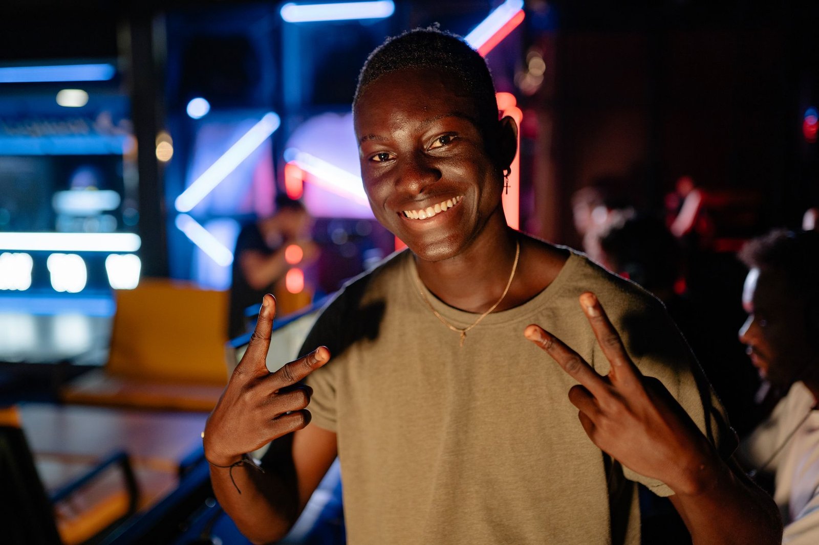Cheerful person enjoying night out in club with vibrant neon lights and joyful gesture.